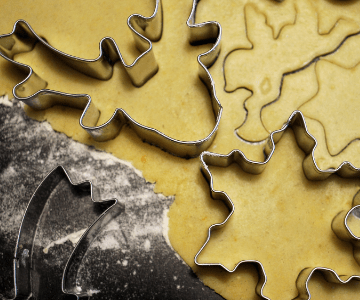 Christmas cookies being cut out of dough