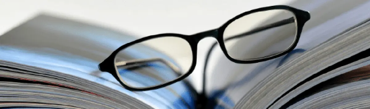 Reading glasses resting on the pages of an open book.